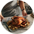 Perfectly browned roasted chicken with vegetables being set on the marble counter